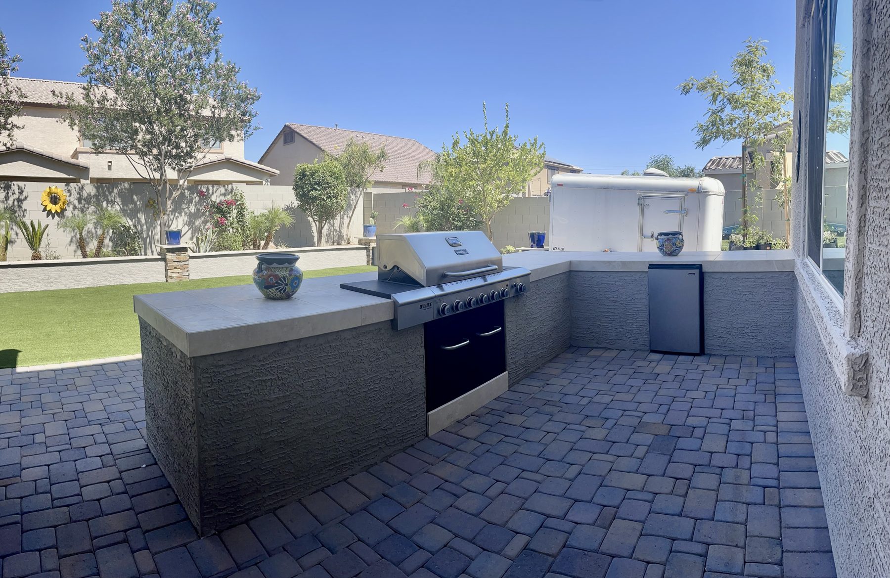 L-shaped outdoor kitchen with grill on a paver patio