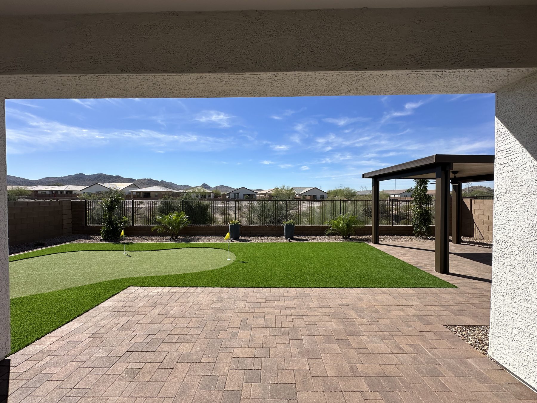 Putting green and paver patio under a steel pergola