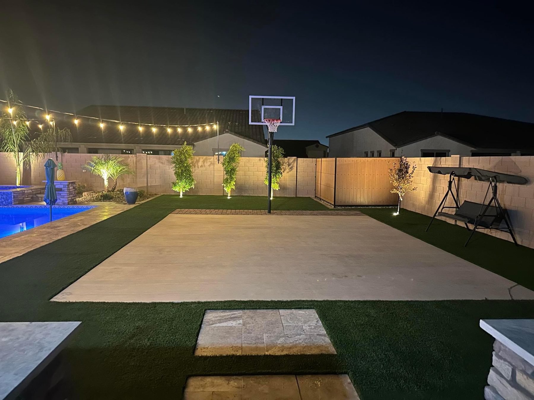 Backyard sport court with string lights at night